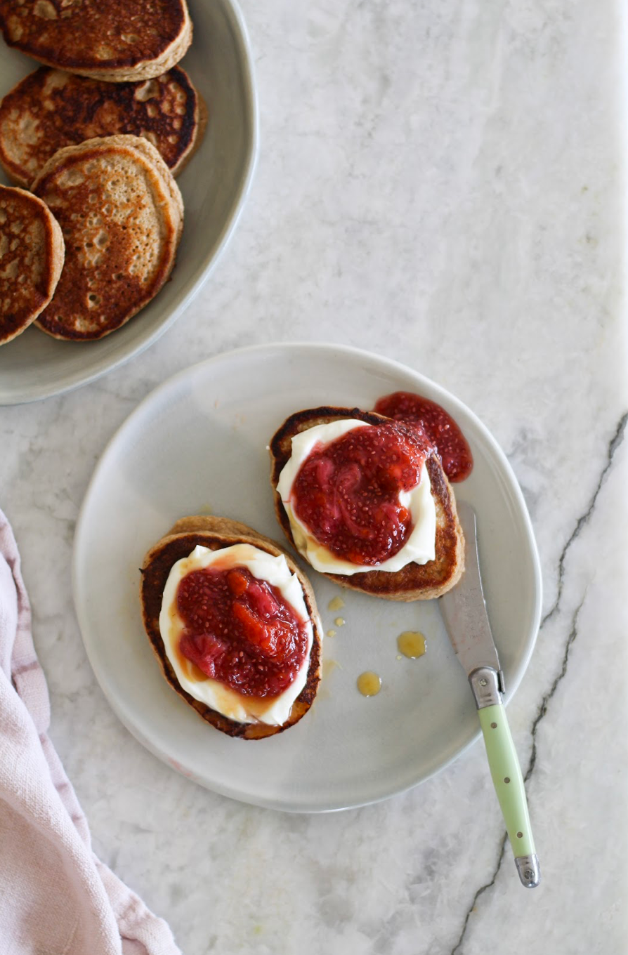 Stack of fluffy banana oat pancakes made with Odi Smoothie Booster - healthy kid-friendly breakfast topped with yogurt and berries
