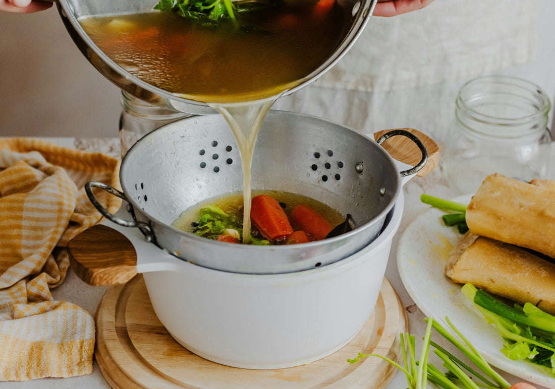 Straining homemade chicken noodle soup broth from whole organic chicken - healing family meal with Odi Meal Booster